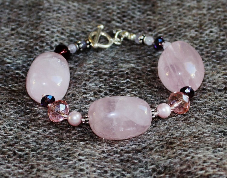 Rannekorussa suurten ruusukvartsihelmien lisäksi Swarovskin huurrekristallihelmiä, pieniä ametistihelmiä, erilaisia lasihelmiä, sekä balin hopea helmiä. Lukko Sterling hopeinen salpalukko.