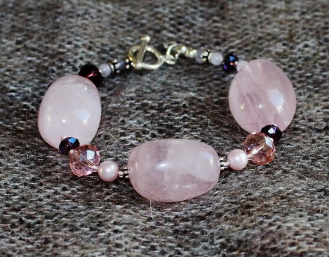 Rannekorussa suurten ruusukvartsihelmien lisäksi Swarovskin huurrekristallihelmiä, pieniä ametistihelmiä, erilaisia lasihelmiä, sekä balin hopea helmiä. Lukko Sterling hopeinen salpalukko.